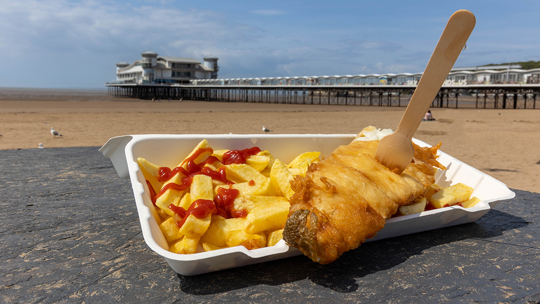 Portion of fish and chips with Weston's Grand Pier in the background